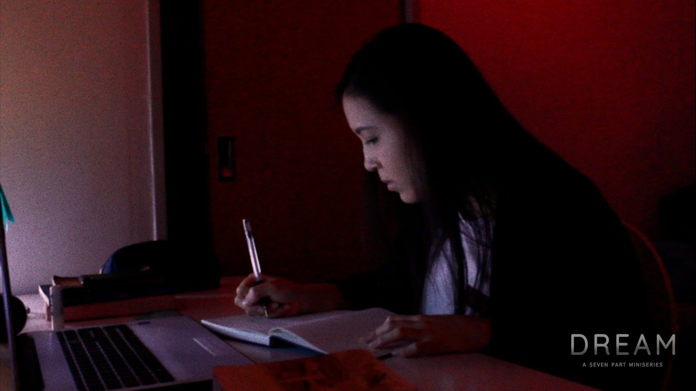 A woman writing at night in a red-lit room